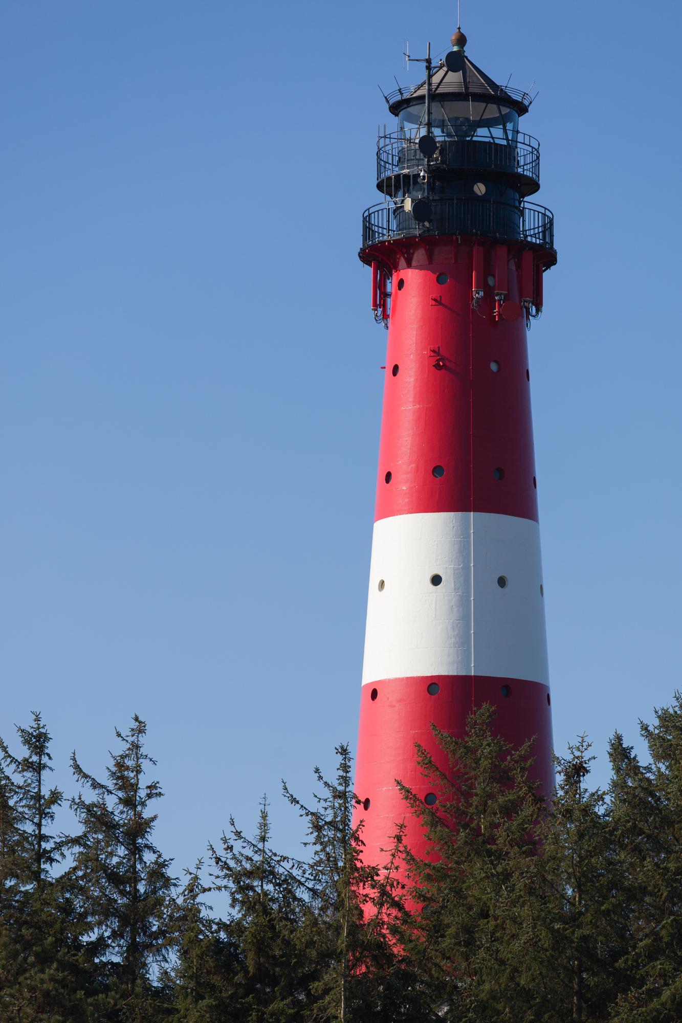 On a sunny day the lighthouse shines in its red and white colours.